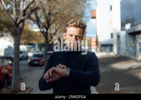 Ein Mann mit Armbanduhr auf dem Fußweg Stockfoto