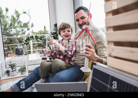 Vater und Sohn, die zu Hause mit Windkraftmodellen spielen Stockfoto