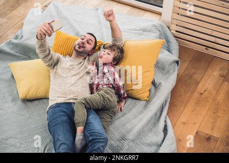 Sohn mit Vater macht Selfie über Smartphone zu Hause Stockfoto