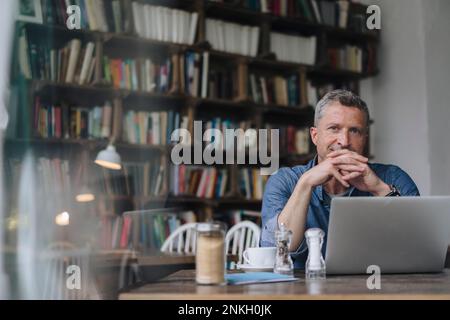 Freiberufler mit Laptop sitzt am Tisch im Café Stockfoto