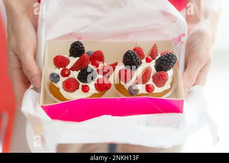 Hände einer Frau, die französische Torten mit frischem Obst hält Stockfoto