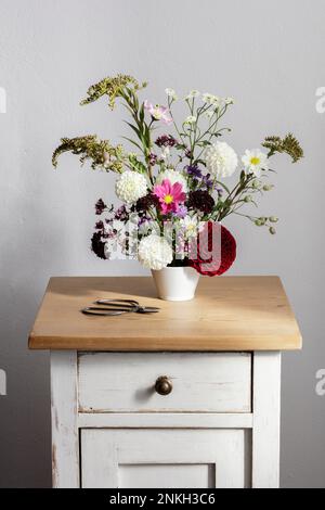 Anordnung von Kräutern und blühenden Herbstblumen auf dem Nachttisch Stockfoto