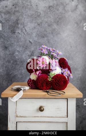 Strauß roter und rosafarbener Blumen der Saison auf dem Nachttisch Stockfoto