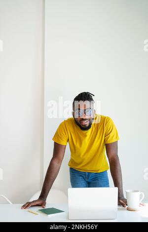 Glücklicher Freiberufler mit Notebook, das im Home Office auf dem Schreibtisch liegt Stockfoto