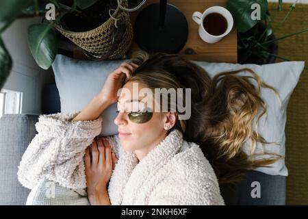 Frau mit Augenklappe, die zu Hause im Bett schläft Stockfoto