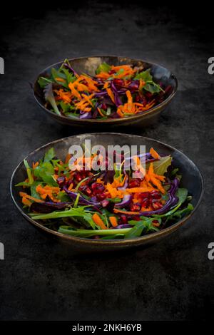 Studioaufnahme von zwei Tellern veganen Salats, die vor schwarzem Hintergrund liegen Stockfoto