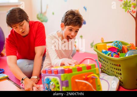 Glückliche Physiotherapeutin und behindertes Mädchen im Rehabilitationszentrum Stockfoto