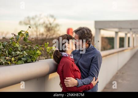 Reifes Paar, das sich am Geländer küsst Stockfoto