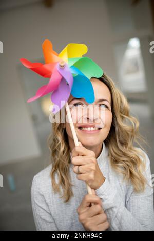 Lächelnde Frau, die ein mehrfarbiges Kleinrad im Gesicht hält Stockfoto