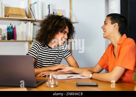 Glückliche Geschäftskollegen, die am Tisch sitzen Stockfoto