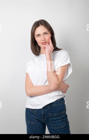 Junge Frau, die auf weißem Hintergrund steht Stockfoto