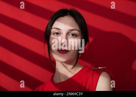 Schöne junge Frau mit rotem Lippenstift auf farbigem Hintergrund Stockfoto