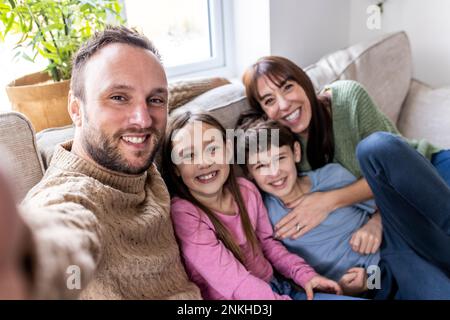Glücklicher Mann, der Selfie mit der Familie zu Hause macht Stockfoto