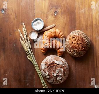 Frisch gebackene Brotlaibe und Croissants auf einem Holztisch Stockfoto