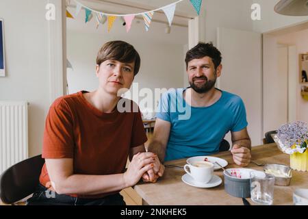 Reifes Paar, das zu Hause mit Frühstück auf dem Esstisch sitzt Stockfoto