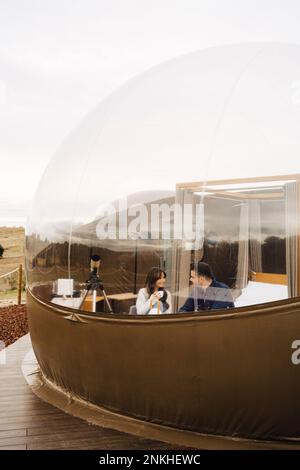 Ein junges Paar, das Kaffee trinkt und im Kuppelhotel sitzt Stockfoto