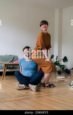 Reifer Mann mit Kreuzbein von Frau im Wohnzimmer zu Hause Stockfoto
