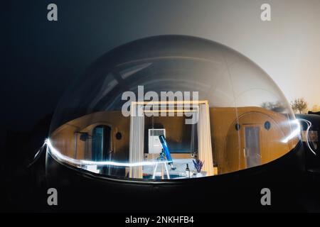 Teleskop auf Stativ im Kuppelzelt mit leichten Wanderwegen bei Nacht Stockfoto