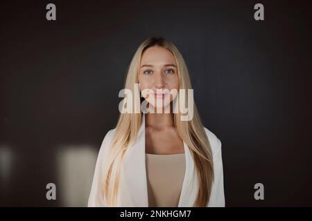 Selbstbewusste blonde Frau vor der schwarzen Wand Stockfoto