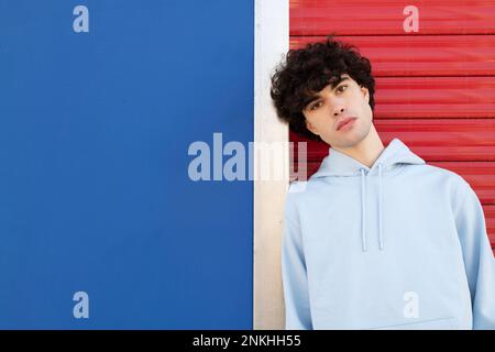 Selbstbewusster junger Mann, der sich an die Wand lehnt Stockfoto