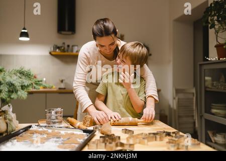 Glücklicher Sohn, der mit Mutter in der Küche Ingwerkekse macht Stockfoto