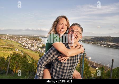 Ein glücklicher, reifer Mann, der an sonnigen Tagen eine Frau mit dem Schweinchen zurückreitet Stockfoto