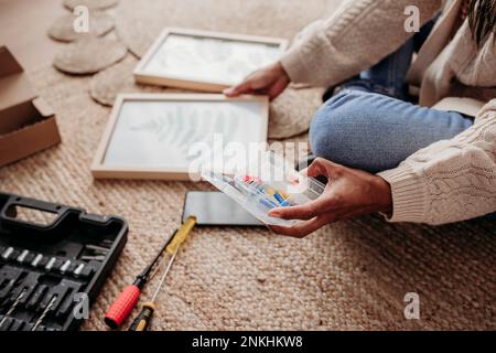 Frau, die Heimwerker-Bilderrahmen macht, sitzt zu Hause Stockfoto