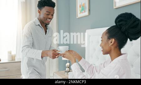 Afrikanische Paare trinken Kaffee im Bett, entspannen mit Tee im Schlafzimmer und glücklich am Morgen im Haus. Mann und Frau mit Drinks zum Frühstück zu Hause Stockfoto