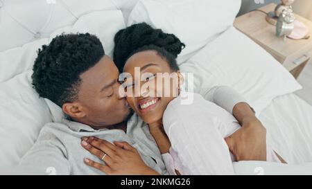 Selfie, Kuss und glückliches Influencer-Paar, das ihre Flitterwochen im Bett bucht, um zu Hause zu lieben und zu entspannen. Porträt eines liebenden Schwarzen Stockfoto