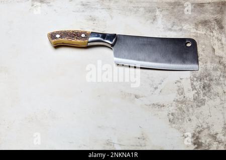 Fleischspalter auf Holzhintergrund. Küchenmesser oder Metzgerspalter aus Edelstahl auf einer Holzplatte Stockfoto