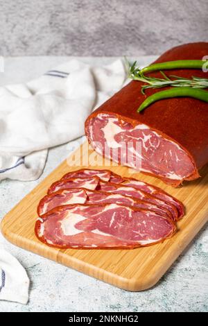 Rinderribeye Pastrami. Getrocknete türkische Speckscheibe auf Holzbrett. Traditionelle türkische Köstlichkeiten. Lokaler Name Cemenli pastirma Stockfoto