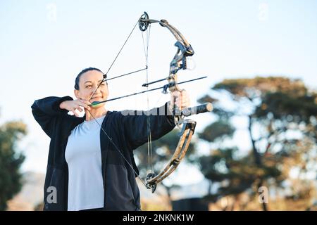 Fröhliche Frau, Bogen oder Pfeile zielen auf Sportplätze, Schießstände oder Spiele in der Jagd, beim Hobby oder beim Sport. Bogenschießen, Person oder Sportler lächeln mit Stockfoto