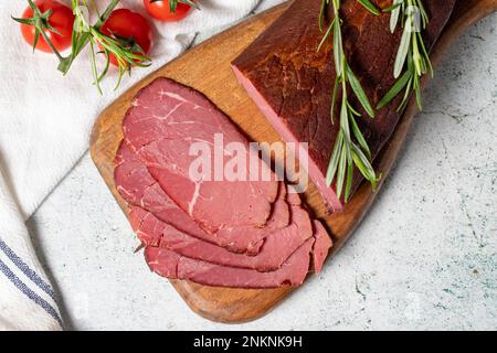 Trockenfleisch. Scheiben getrockneten und geräucherten Trockenfleisches auf einem Holzbrett. Rinderwürstchen. Draufsicht Stockfoto