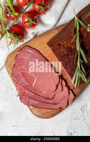 Trockenfleisch. Scheiben getrockneten und geräucherten Trockenfleisches auf einem Holzbrett. Rinderwürstchen. Draufsicht Stockfoto