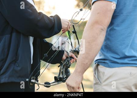 Schießstand, Bogenschießen und Bogenschießen, Sporttraining mit einer Frau und einem Mann im Freien für Zielübungen. Die Hände des Bogenschützen und Sportlers für den Wettkampf Stockfoto