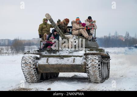 KRASNOYE SELO, RUSSLAND - 19. FEBRUAR 2023: Besucher des historischen Militärparks „Steel Landing“ fahren an einem Nachmittag im Februar in einem sowjetischen Panzer mit T-54 Stockfoto