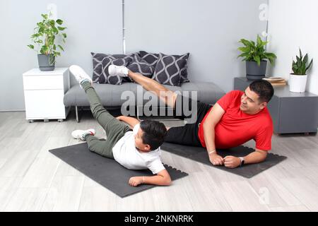 Übergewicht Latino Dad und Sohn Übung zu Hause, Gewicht zu verlieren und gesund zu sein, um Krankheiten wie Diabetes oder Bluthochdruck zu vermeiden Stockfoto