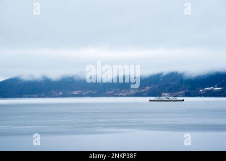 Autofähre im norwegischen Fjord mit niedrigen schweren Wolken Stockfoto