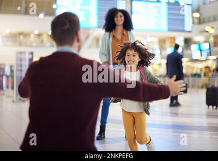 Glückliches Kind, das zum Vater am Flughafen rennt, um eine willkommene Heimreise und ein Wiedersehen, Einwanderung oder internationale Gelegenheit zu erleben. Gemischtrassige Familie, Dad und Stockfoto