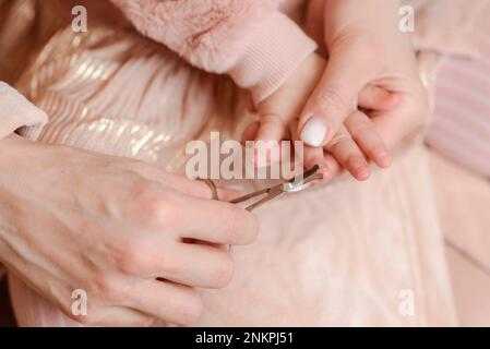 Eine Frau schneidet ihrer kleinen Tochter zu Hause die Nägel durch Stockfoto