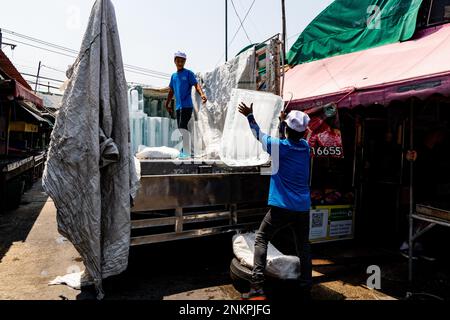 Lad Krabang, Thailand, 24/02/2023, Arbeiter transportieren große Eisblöcke von einem Lkw auf einen Markt im Freien. Das tägliche Leben rund um Lad Krabang, ein Wohnviertel in der Nähe des internationalen Flughafens Suvarnabhumi, in East Bangkok, Thailand, am 24. Februar 2022. Stockfoto