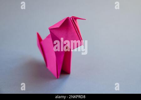 Rosa Papier Hund Origami isoliert auf einem weißen grauen Hintergrund. Stockfoto