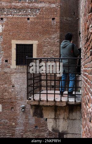 Person, die auf einem Balkon mit Blick auf die Architektur von Castelvecchio steht. Blick auf Touristen von der historischen Struktur. Stockfoto