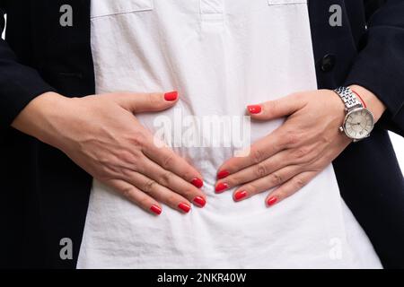 Nahaufnahme eines erwachsenen Unternehmermodells mit schmerzhaftem Bauch und abdominellen pms-Schmerzen auf weißem Studiohintergrund Stockfoto