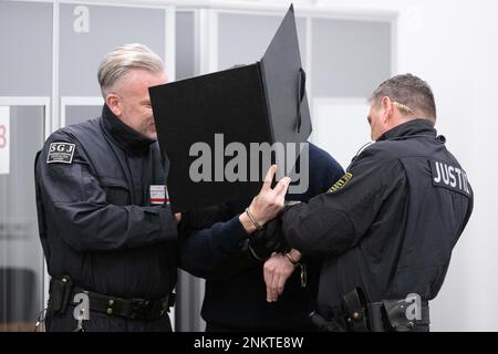 Dresden, Deutschland. 24. Februar 2023. Ein Angeklagter (M), der im Prozess des Juwelendiebstahls im Grünen Gewölbe des Residenzpalastes Dresden steht, wird in den Verhörraum des Landesgerichts geführt. Sechs Männer stehen vor Gericht wegen des spektakulären Einbruchs im Staatsmuseum, in dem Juwelen aus dem 18. Jahrhundert gestohlen wurden. Kredit: Sebastian Kahnert/dpa-Pool/dpa/Alamy Live News Stockfoto