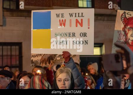 New York, Usa. 23. Februar 2023. Eine Frau hält ein Plakat bei einer Kerzenlichtwache am Vorabend des einjährigen Jubiläums der russischen Invasion vor dem russischen Konsulatgebäude auf der Upper East Side in Manhattan in New York City. Ukrainer und Russen sprechen sich gegen den Krieg aus, Putin und trauern um die Opfer der Invasion. Kredit: SOPA Images Limited/Alamy Live News Stockfoto