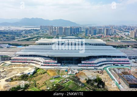 Fuzhou. 21. Februar 2023. Dieses Luftfoto wurde am 21. Februar 2023 aufgenommen und zeigt den im Bau befindlichen Südbahnhof Fuzhou in Fuzhou, der südöstlichen chinesischen Provinz Fujian. Die 277 km lange Eisenbahnstrecke verläuft entlang der südostchinesischen Küste und durchquert drei große Buchten auf gigantischen Brücken. Es ist die erste Hochgeschwindigkeitsbahn des Landes, die das Meer überquert. Mit einer geplanten Geschwindigkeit von 350 km/h und acht Stationen entlang der Route wird die Reisezeit zwischen den beiden Städten voraussichtlich auf nur eine Stunde verkürzt. Kredit: Lin Shanchuan/Xinhua/Alamy Live News Stockfoto