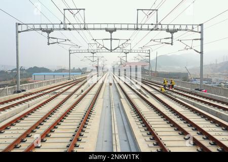 Fuzhou. 19. Februar 2023. Dieses Luftfoto wurde am 19. Februar 2023 aufgenommen und zeigt die Baustelle in der Nähe des Westbahnhofs Fuqing der neuen Hochgeschwindigkeitsbahn Fuzhou-Xiamen in der Provinz Fujian im Südosten Chinas. Die 277 km lange Eisenbahnstrecke verläuft entlang der südostchinesischen Küste und durchquert drei große Buchten auf gigantischen Brücken. Es ist die erste Hochgeschwindigkeitsbahn des Landes, die das Meer überquert. Mit einer geplanten Geschwindigkeit von 350 km/h und acht Stationen entlang der Route wird die Reisezeit zwischen den beiden Städten voraussichtlich auf nur eine Stunde verkürzt. Kredit: Lin Shanchuan/Xinhua/Alamy Live News Stockfoto