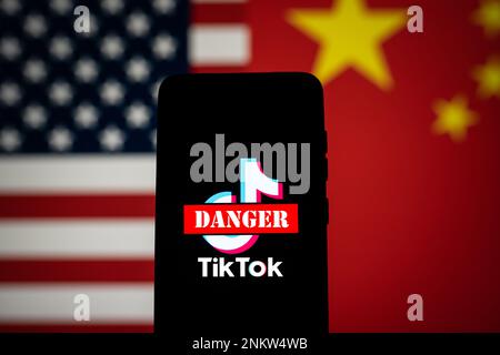 Das Logo der TikTok App ist mit einem roten Gefahrenschild auf dem Bildschirm des Telefons mit den US- und China-Flaggen durchstrichen. TIK Tok Ban im US-Konzept. Swansea, Großbritannien - 23. Februar 2023. Stockfoto