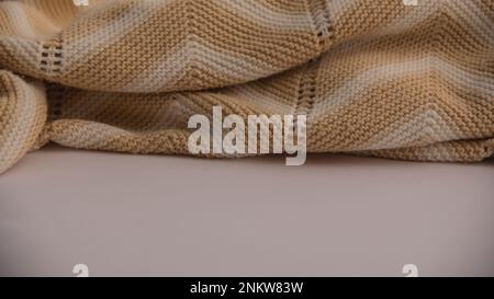 Beige gestrickt mit weißen Streifen auf einer weißen Oberfläche mit Kopierbereich. Herbst, Winter, flach liegend, Draufsicht Stockfoto